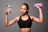 Happy healthy black asian woman with water and dumbbell