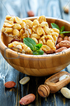 Honey bars with peanuts and peanut fruits in a wooden bowl.