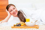 happy beautiful girl on the bed with a tray of food