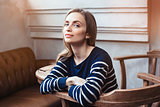 Portrait of smiling female hipster waiting for meeting with best friend while during coffee break in cafe. Grey background with copy space area for advertising content