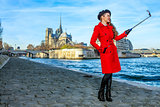 smiling tourist woman in Paris taking selfie using selfie stick