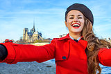 smiling woman on embankment in Paris, France taking selfie