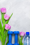 Spring flatlay sports composition with blue dumbbells and purple