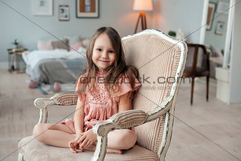 Portrait of a cute little girl sitting in the chair in her room