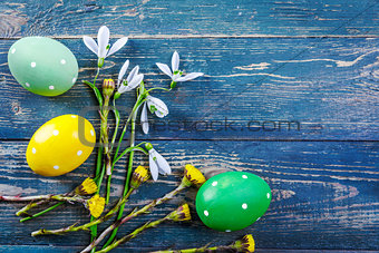 Easter eggs and spring flower snowdrop on old wooden blue