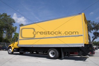 A yellow box delivery truck with blue sky
