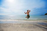 man jumping by the beach happily