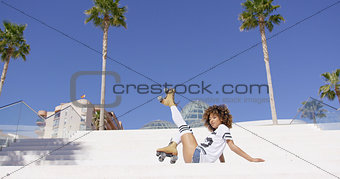 Female wearing roller skates sitting on stairs