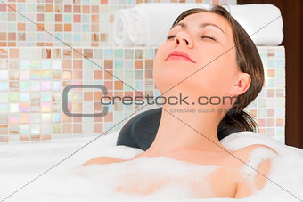 Happy relaxed woman relaxing in the bath with foam