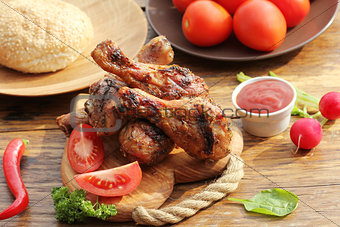 Grilled chicken legs on cutting board.Rustic dinner background.