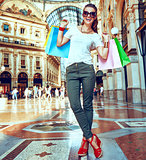 Happy fashion woman in eyeglasses with shopping bags in Galleria
