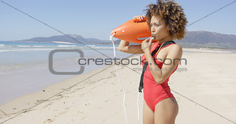 Lifeguard blowing a whistle holding rescue float