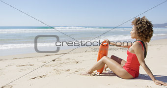 Female with rescue float sitting on beach