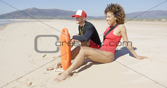 Male and female lifeguards sitting on beach