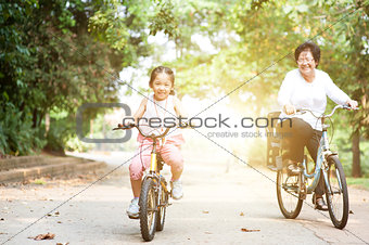 Grandmother and granddaughter biking outdoor.