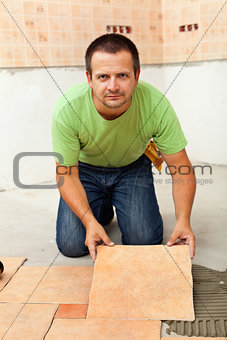 Man laying ceramic floor tiles