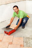Man cutting ceramic floor tiles with electric cutter