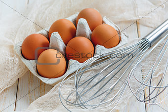 Brown eggs with stainless steel whisk.