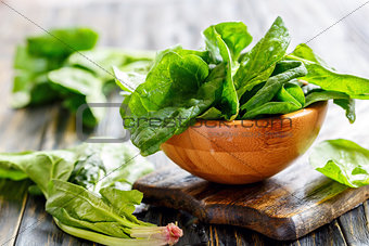 Wooden bowl with fresh spinach leaves.