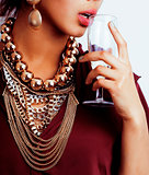 young african-american woman drinking champagne, holding glass, wearing lot of golden jewelry