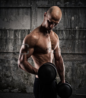 Athletic man training biceps on grunge background