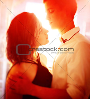 Young people hugging in the apartment in the evening in the rays of the sunset