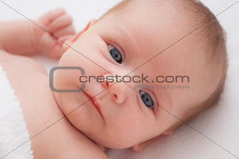 Cute adorable newborn baby girl in white bed and looking at the camera