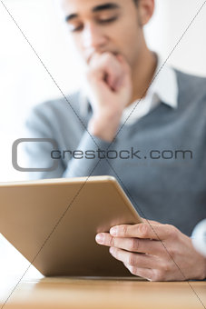 Pensive man looking at tablet