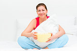 smiling brunette with a bowl of popcorn watching tv