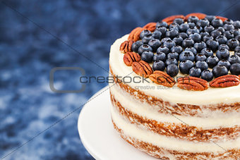 Naked carrot cake decorated with fresh blueberry and pecan