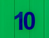 the number ten blue, set against bright green wood