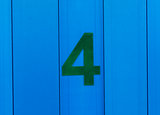 the number four, green, set against bright blue wood
