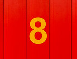 the number eight, yellow, set against bright red wood