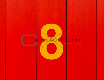 the number eight, yellow, set against bright red wood
