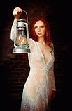 Portrait of lovely young redhead woman with kerosene lamp
