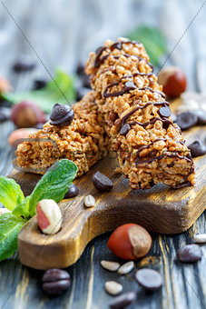 Cereal bars with chocolate and nuts on a wooden board.