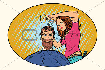 Woman hairdresser cuts the bearded hipster
