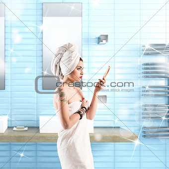 Woman with tattoo washes in the bathroom wrapped in a towel