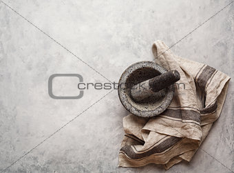 Empty granite mortar and kitchen towel on a gray textured background