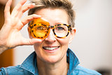 woman with glasses looking through orange glass