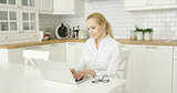 Young woman using laptop at kitchen