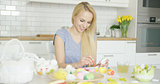 Cheerful woman painting Easter eggs