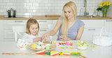 Charming mother and daughter coloring eggs