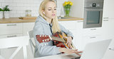 Girl practicing guitar and using laptop