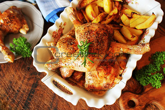 Grilled chicken leg with potato for garnish. Top view. Wooden background.