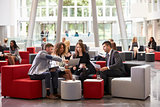 Businesspeople Meeting In Busy Lobby Of Modern Office