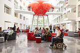 Student in wheelchair and colleagues in university lobby