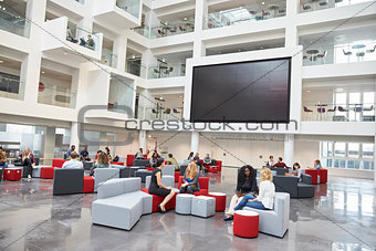 Students meeting in front of screen in atrium at university