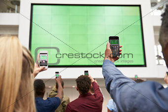 Students photograph screen with phones, back view, close up