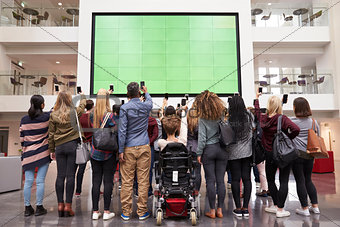 Students photograph screen with phones, back view full length